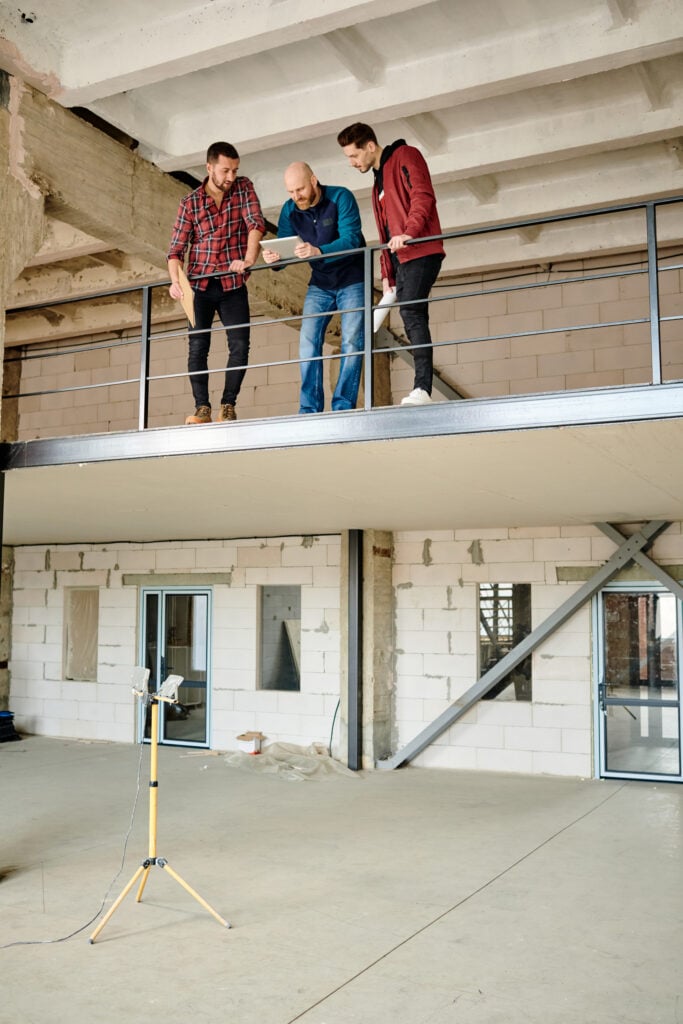 Group of three architects working on the second floor of unfinished building Mezzanine floor in a warehouse